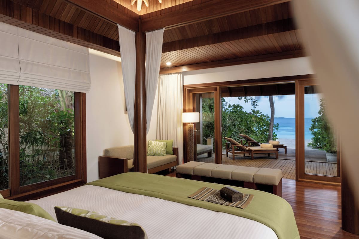 A bedroom with a large bed, a sofa, and a view of the beach.