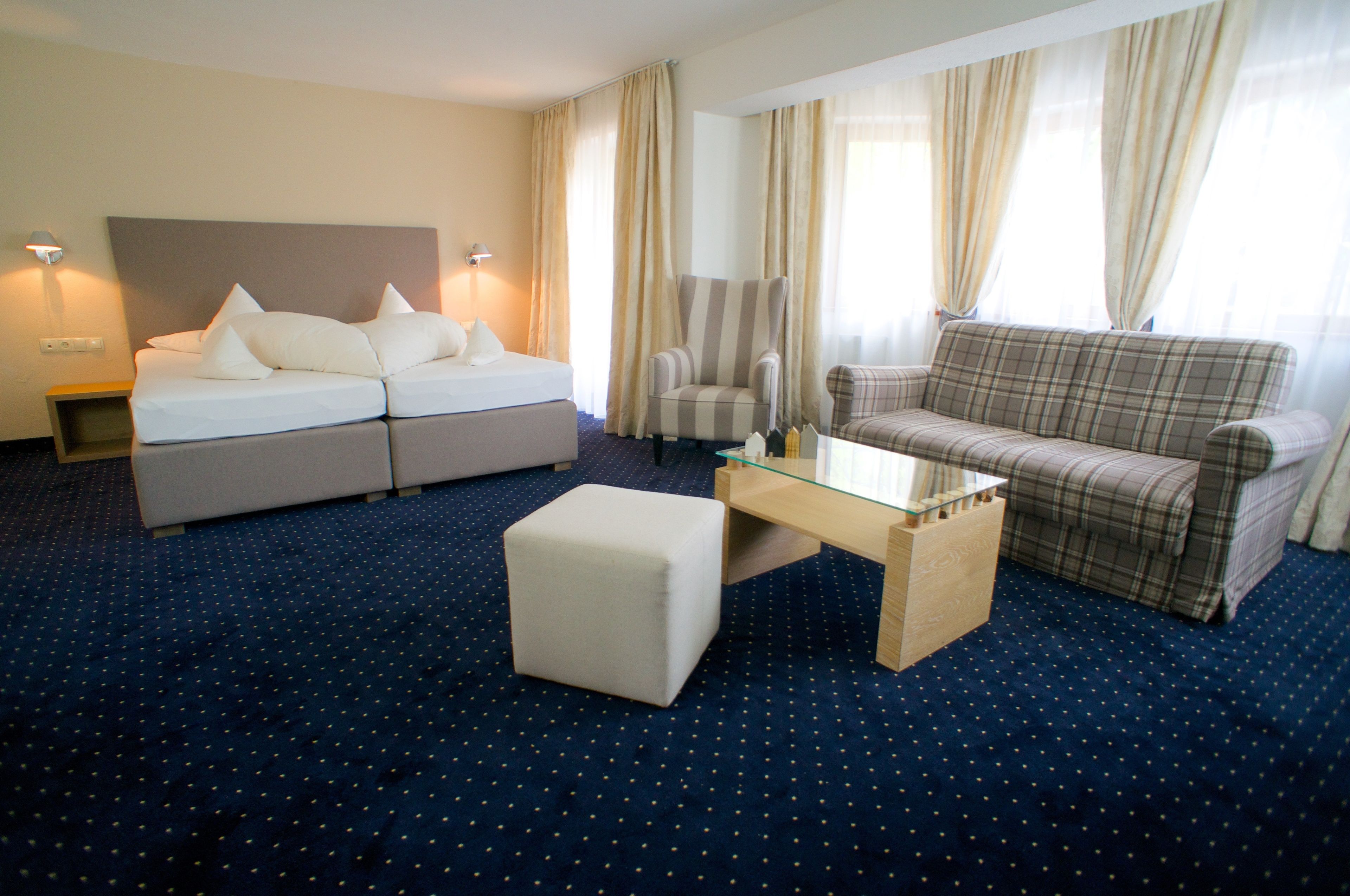 Una habitación de hotel con una cama, un sofá, una silla y una mesita.