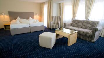 Una habitación de hotel con una cama, un sofá, una silla y una mesita.