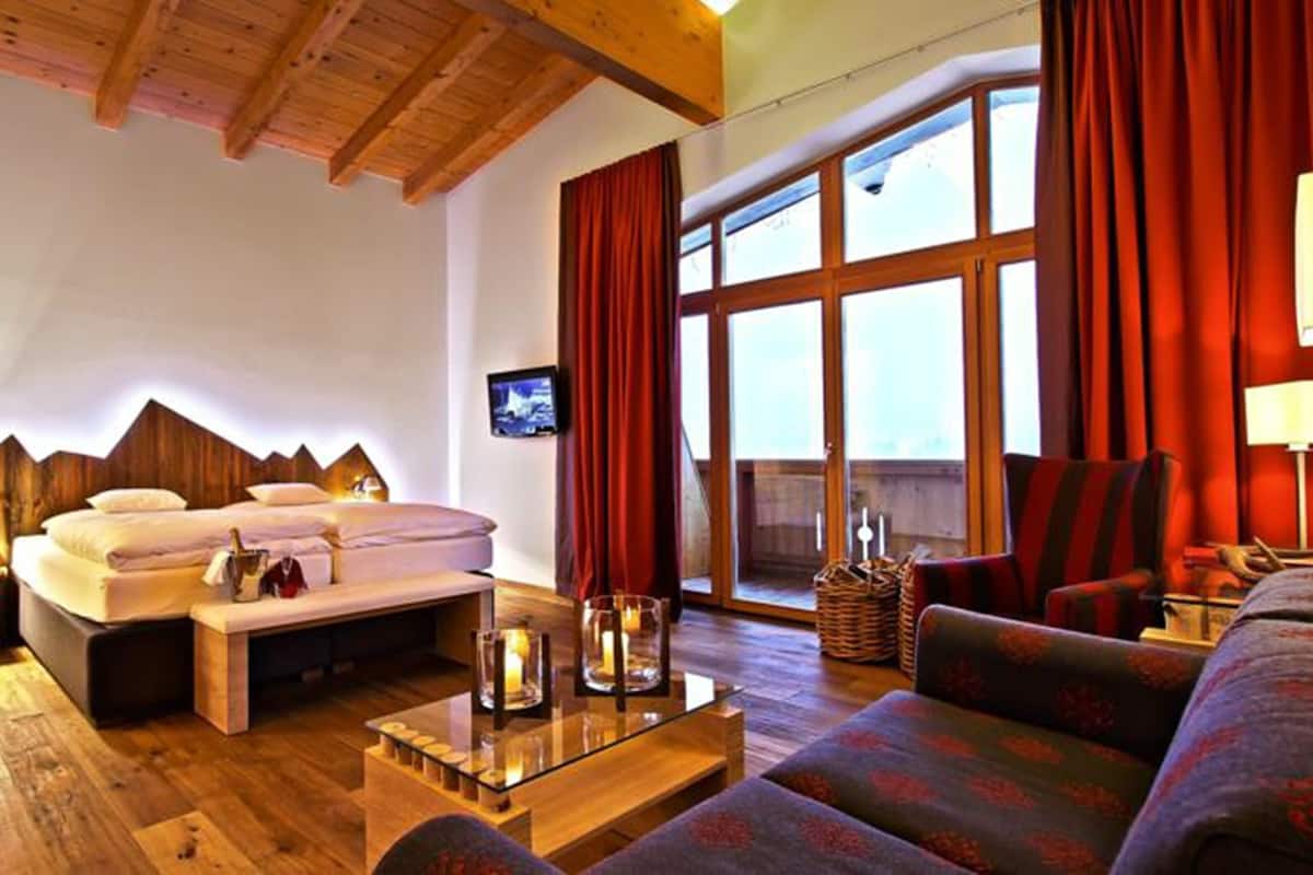 Ein gemütliches Zimmer mit einem Bett, einer Couch, einem Couchtisch und einem Fernseher.