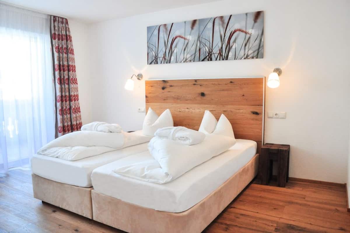 Ein Doppelbett mit weißer Bettwäsche und Kissen, ein Holzkopfteil und zwei Wandleuchten.