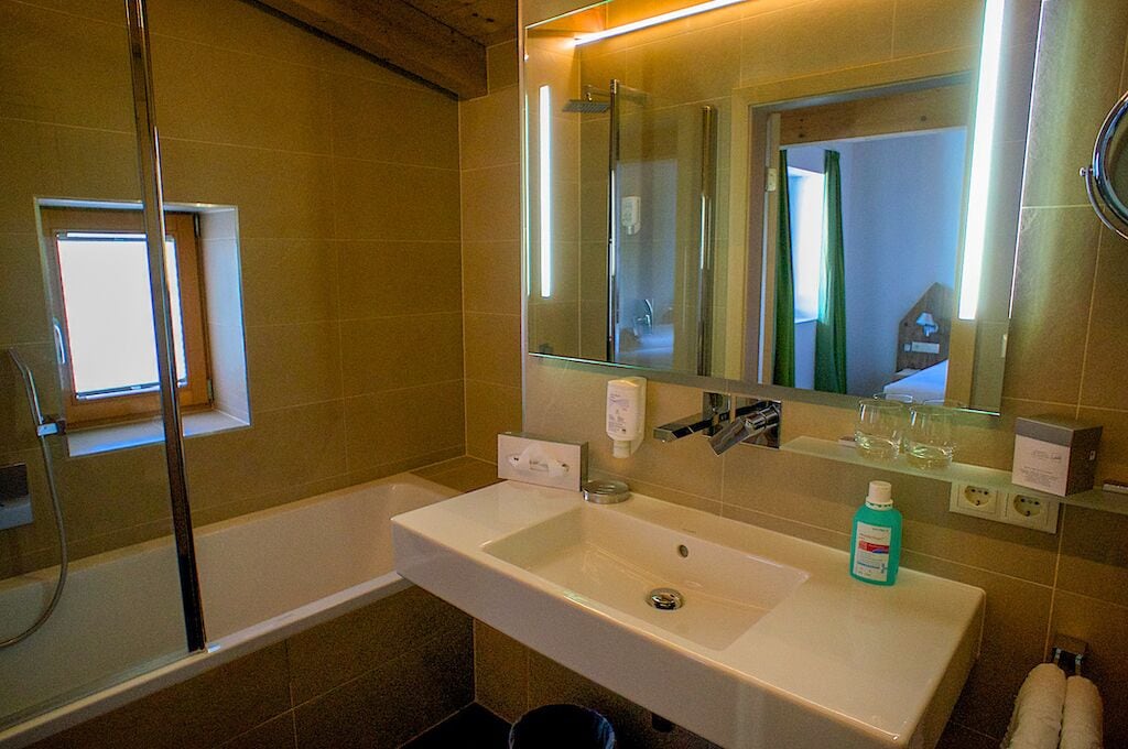 Une salle de bain avec une baignoire, un lavabo, un miroir et une fenêtre.
