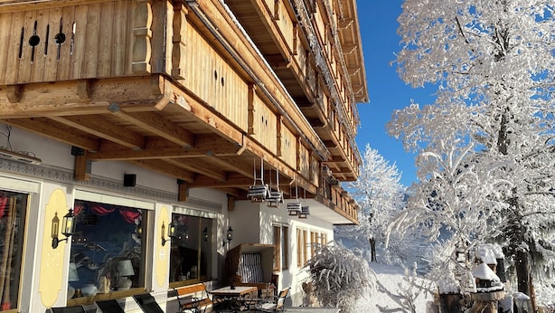 A wooden building with balconies, benches, and a snow-covered path. - Seelos (Seefeld in Tirol)