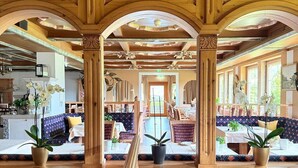 A wooden interior with a central dining area, seating arrangements, and potted plants. - Seelos (Seefeld in Tirol)