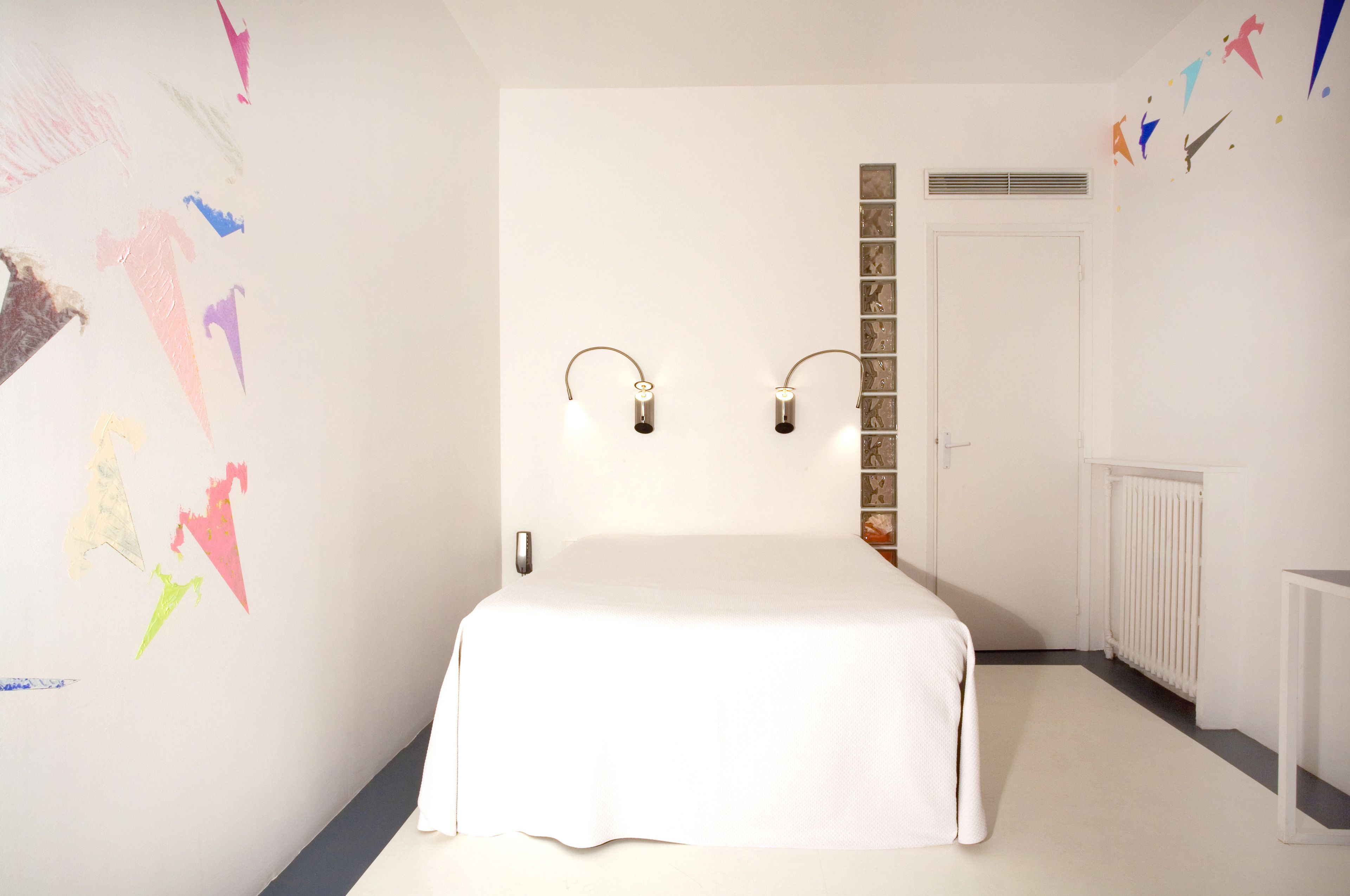 Ein Schlafzimmer mit einem Bett, zwei Wandleuchten, einer Heizung und einer Tür.