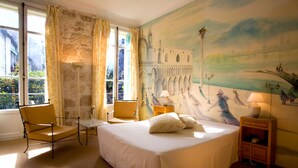 A hotel room with a bed, a chair, a table, and a nightstand. - Windsor Hotel (Nice)