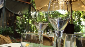 A table set with wine glasses, cutlery, and a yellow napkin, under a tree with a canopy. - Windsor Hotel (Nice)