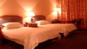 A hotel room with two beds, bedside lamps, a chair, and a table. - Shanghai Changhang Hotel (Shanghai)