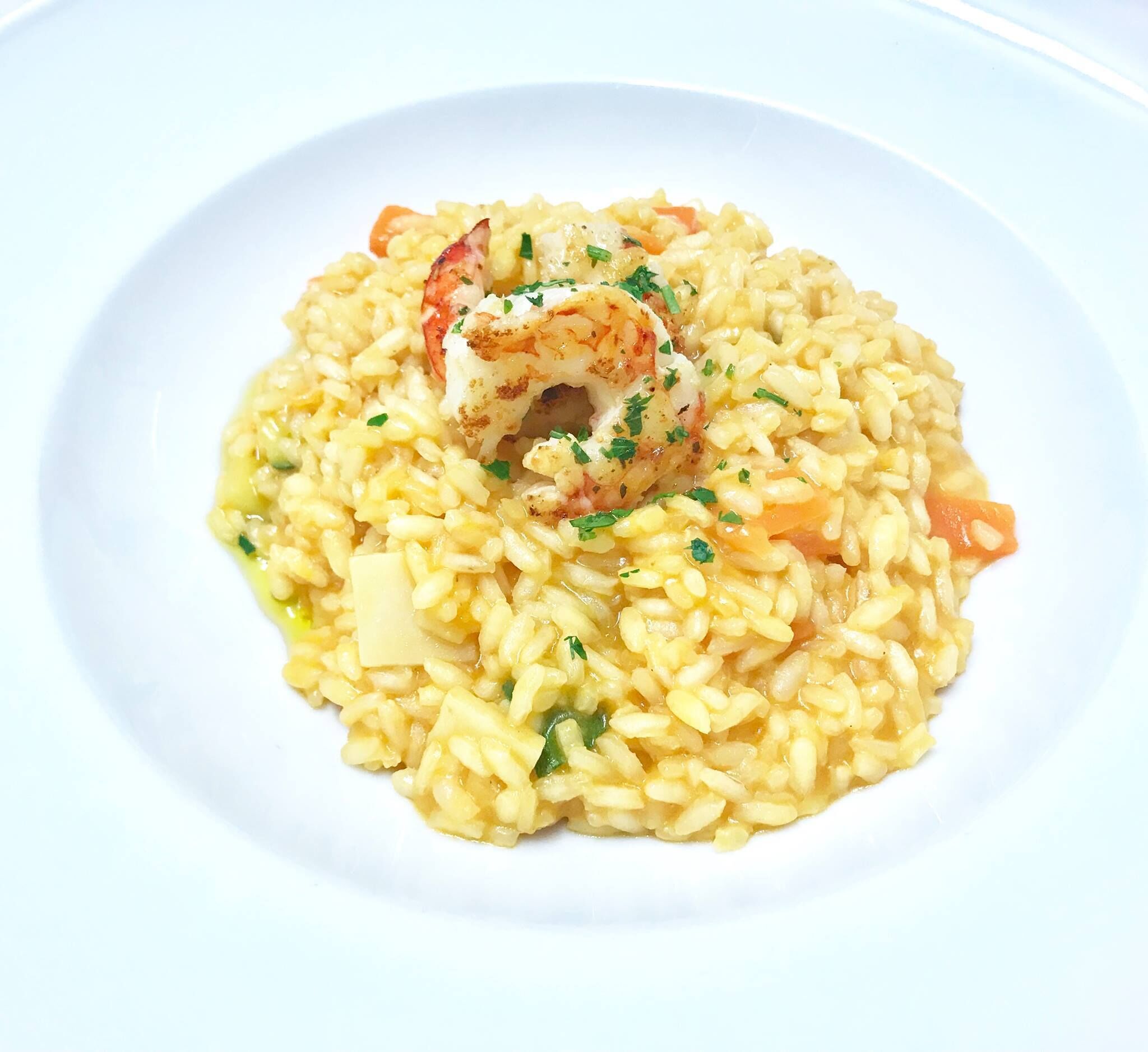A plate of risotto with shrimp and vegetables.