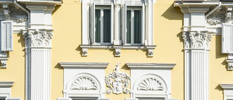 Un edificio amarillo con detalles blancos y molduras decorativas.