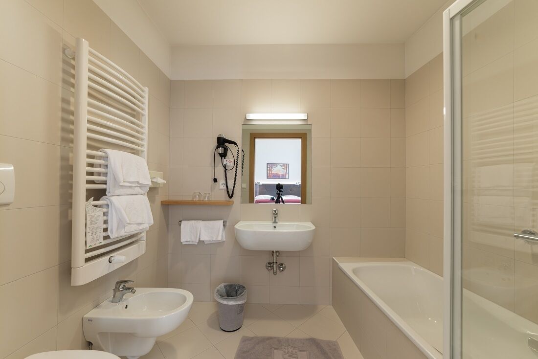 A modern bathroom with a bathtub, two sinks, a vanity with a mirror, and a towel rack.