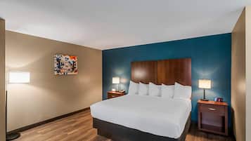 A hotel room with a large bed, two bedside tables with lamps, a nightstand, and a wall-mounted artwork.