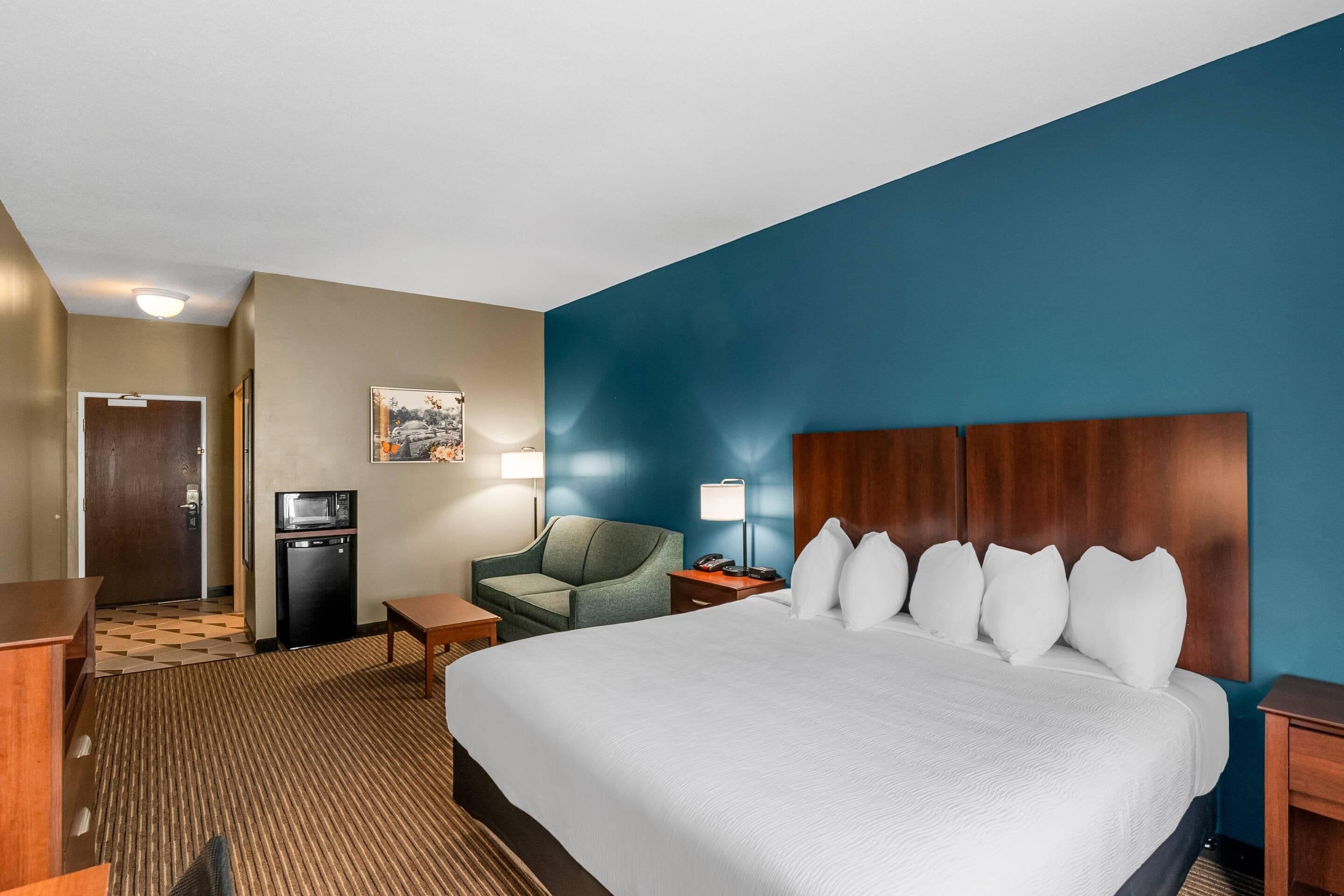 A hotel room with a large bed, a desk, a chair, a microwave, and a small TV.