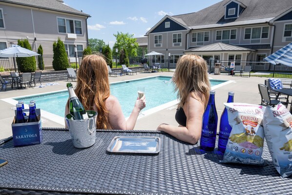 Escena junto a la piscina con una mesa, botellas y bolsas.