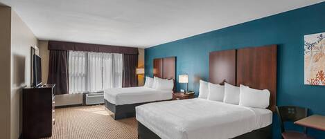A hotel room with two beds, a desk, a chair, a TV, and a window with curtains.