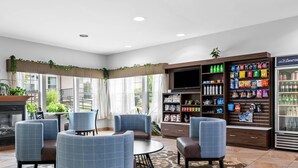 A hotel lobby with a seating area, a TV, a snack bar, and a refrigerator. - The Hotel Saratoga, an Ascend Collection Hotel (Saratoga Springs)