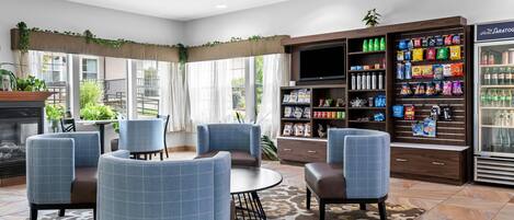 Un hall de hotel con zona de estar, televisión, bar de aperitivos y refrigerador.
