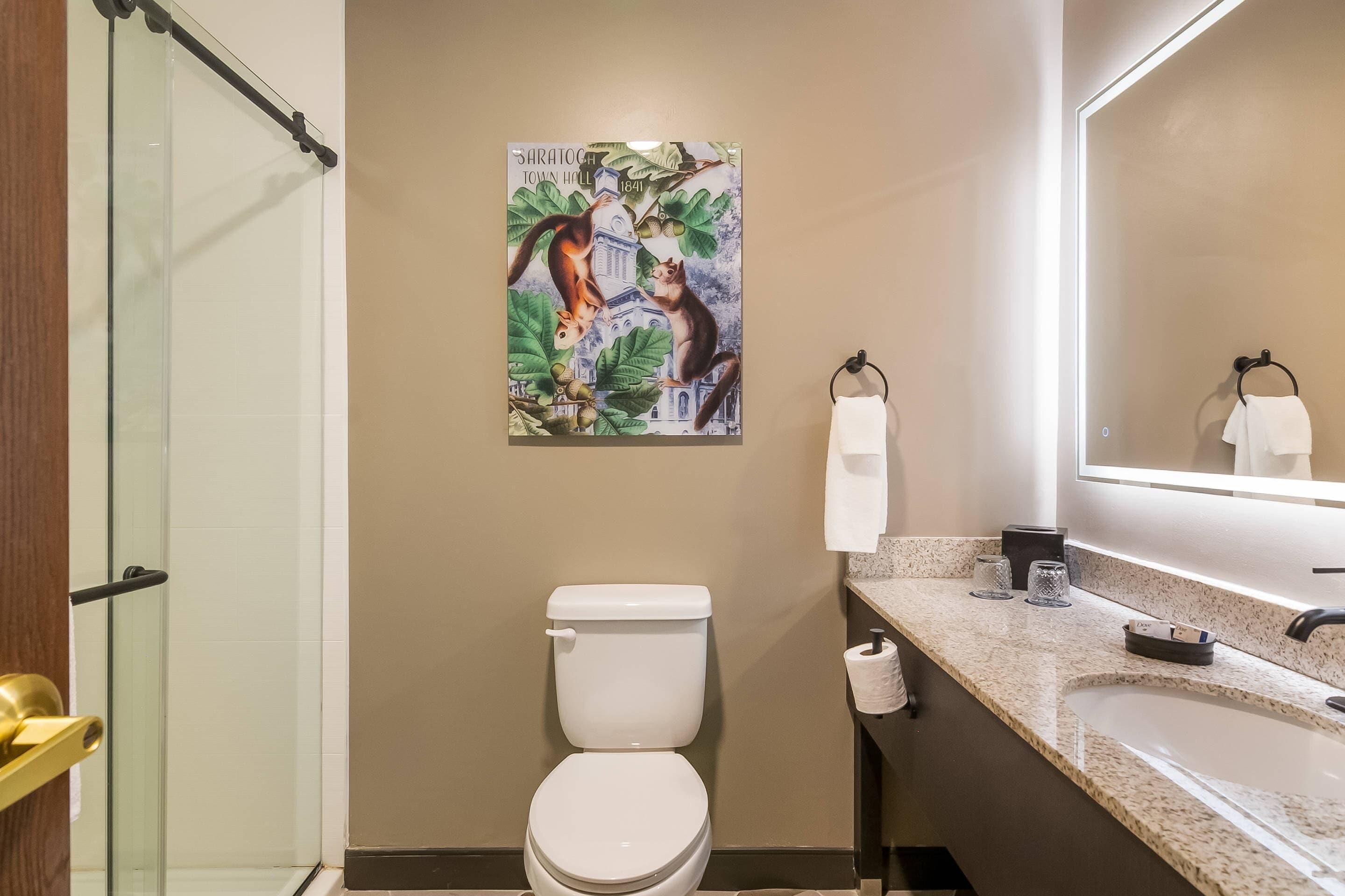 Un baño con inodoro, lavamanos, espejo y ducha.