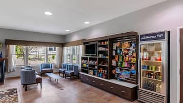 A hotel lobby with seating, a snack bar, a TV, and a refrigerator.