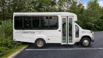 Un autobús blanco con la marca 'The Saratoga' estacionado al costado de una carretera.