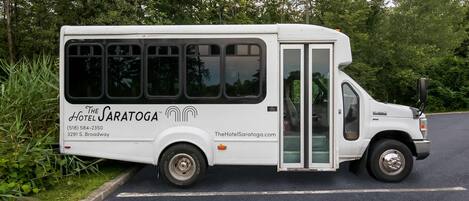 Un autobús blanco con la marca 'The Saratoga' estacionado al costado de una carretera.