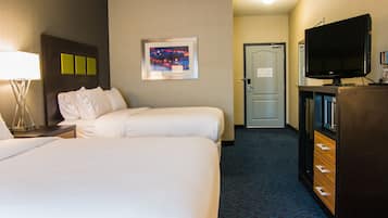 A hotel room with two beds, a television, a desk with a lamp, and a door leading to another room.