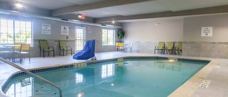 An indoor swimming pool with clear signage, including a lifeguard warning and no diving allowed.