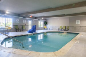 Una piscina interior con señalización clara, que incluye un aviso de socorrista y prohibido bucear.