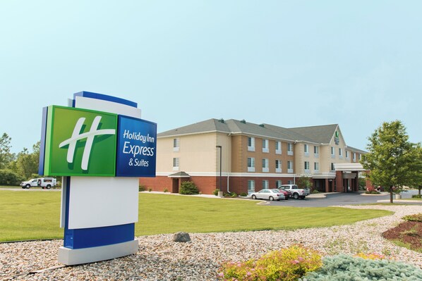 A hotel sign with a green and blue design, a parking lot, and a building with multiple windows.