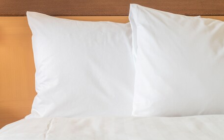 A bed with white bedding and a wooden headboard.
