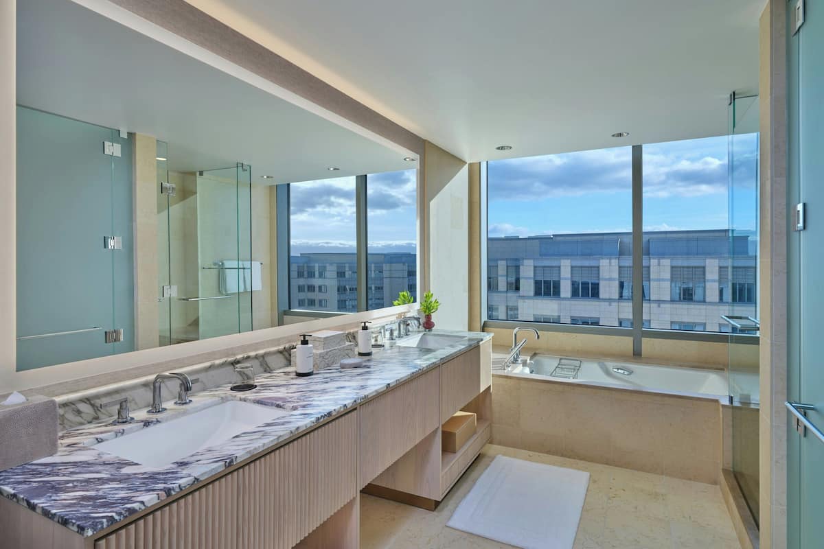 Ein modernes Badezimmer mit einem großen Spiegel, zwei Waschbecken und einer Badewanne.
