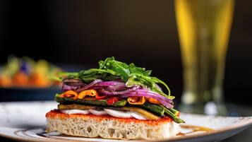 Ein Sandwich mit verschiedenen Gemüsesorten und ein Glas Weißwein auf einem Teller.