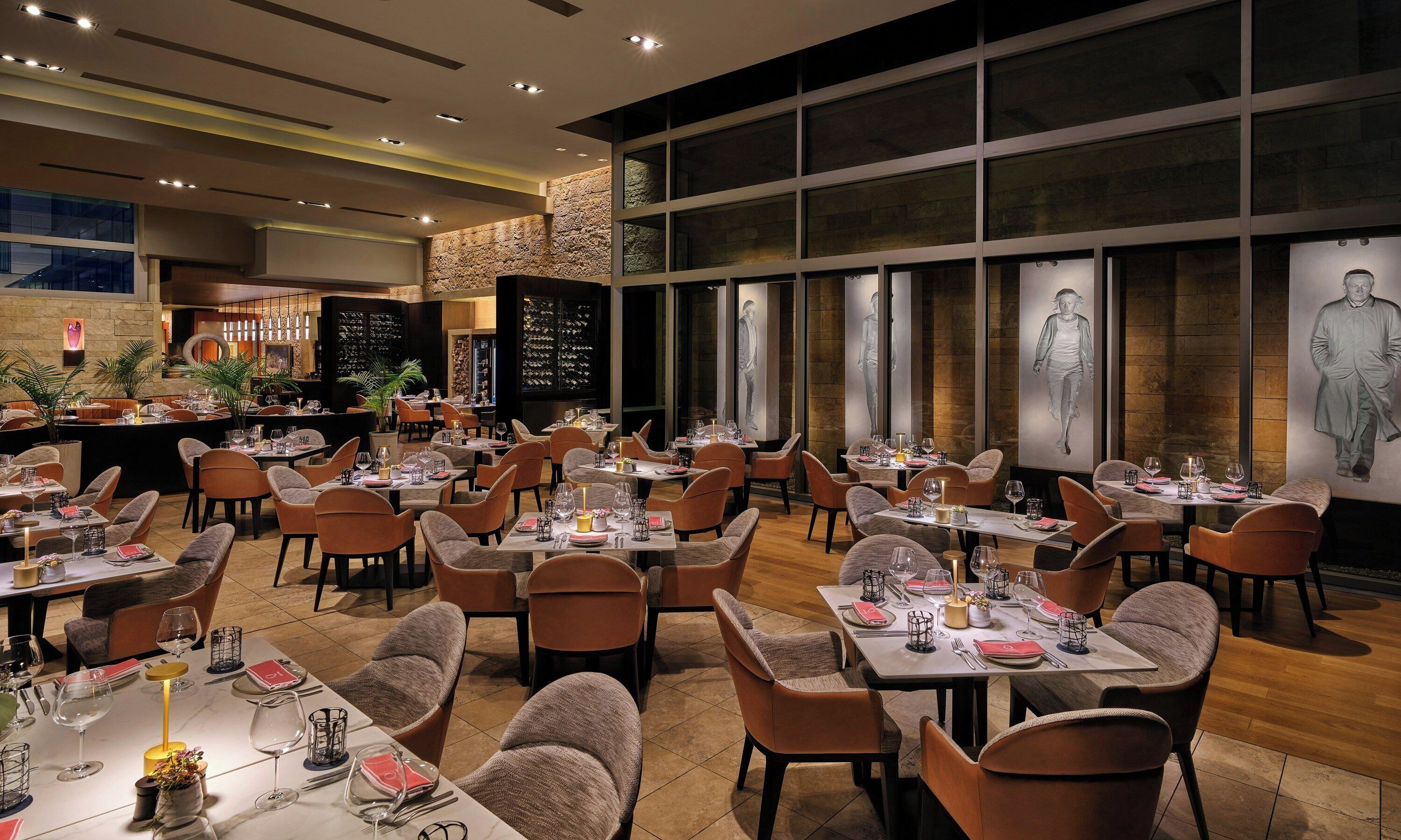 Un restaurante con varias mesas, sillas y una zona de bar.