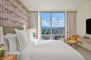A hotel room with a large bed, a desk, a chair, and a TV.