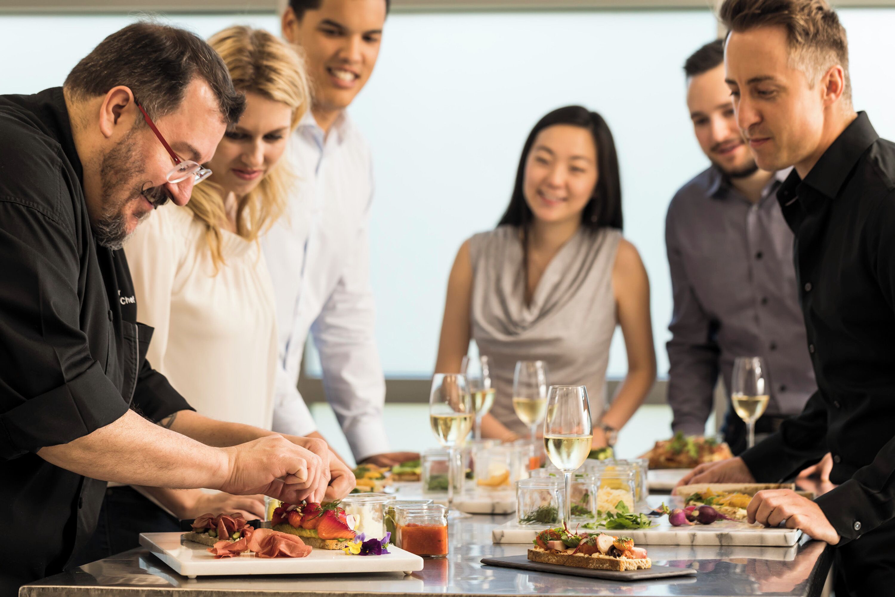 Un grupo de personas cenando en una mesa con diferentes platos y copas de vino.