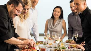 Un grupo de personas cenando en una mesa con diferentes platos y copas de vino.
