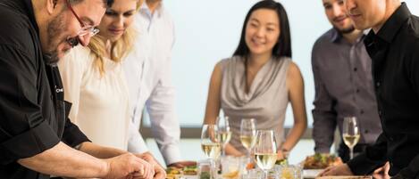 Un grupo de personas cenando en una mesa con diferentes platos y copas de vino.