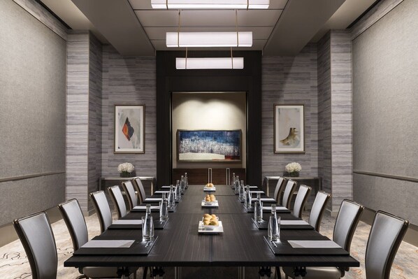A conference room with a long table, chairs, and artwork on the walls.