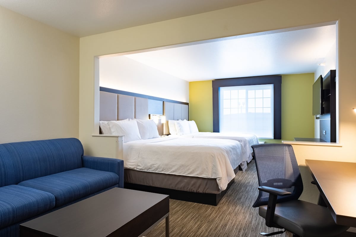 Una habitación de hotel con una cama, un sofá azul, un escritorio y una silla.