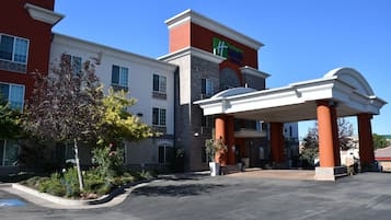 A Holiday Inn Express hotel with a covered entrance, a parking lot, and a landscaped area with trees and shrubs.