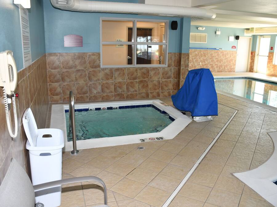 Area piscina con vasca idromassaggio coperta, spogliatoio e porta di uscita.