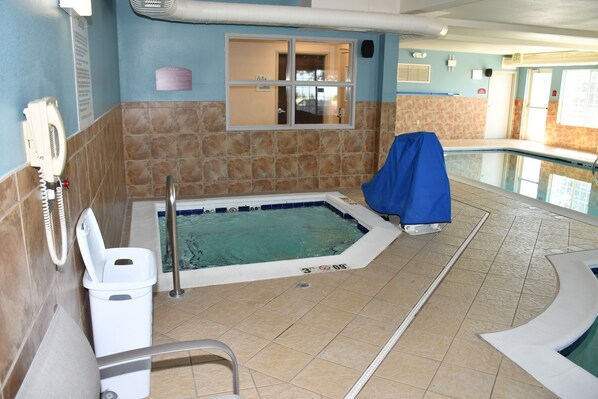 A swimming pool area with a covered hot tub, a changing room, and a visible exit door.