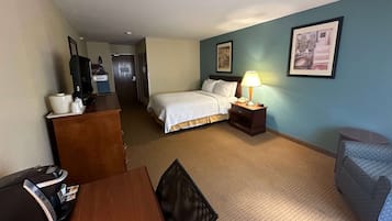 Ein Hotelzimmer mit Bett, Schreibtisch, Stuhl, Lampe und Fernseher.
