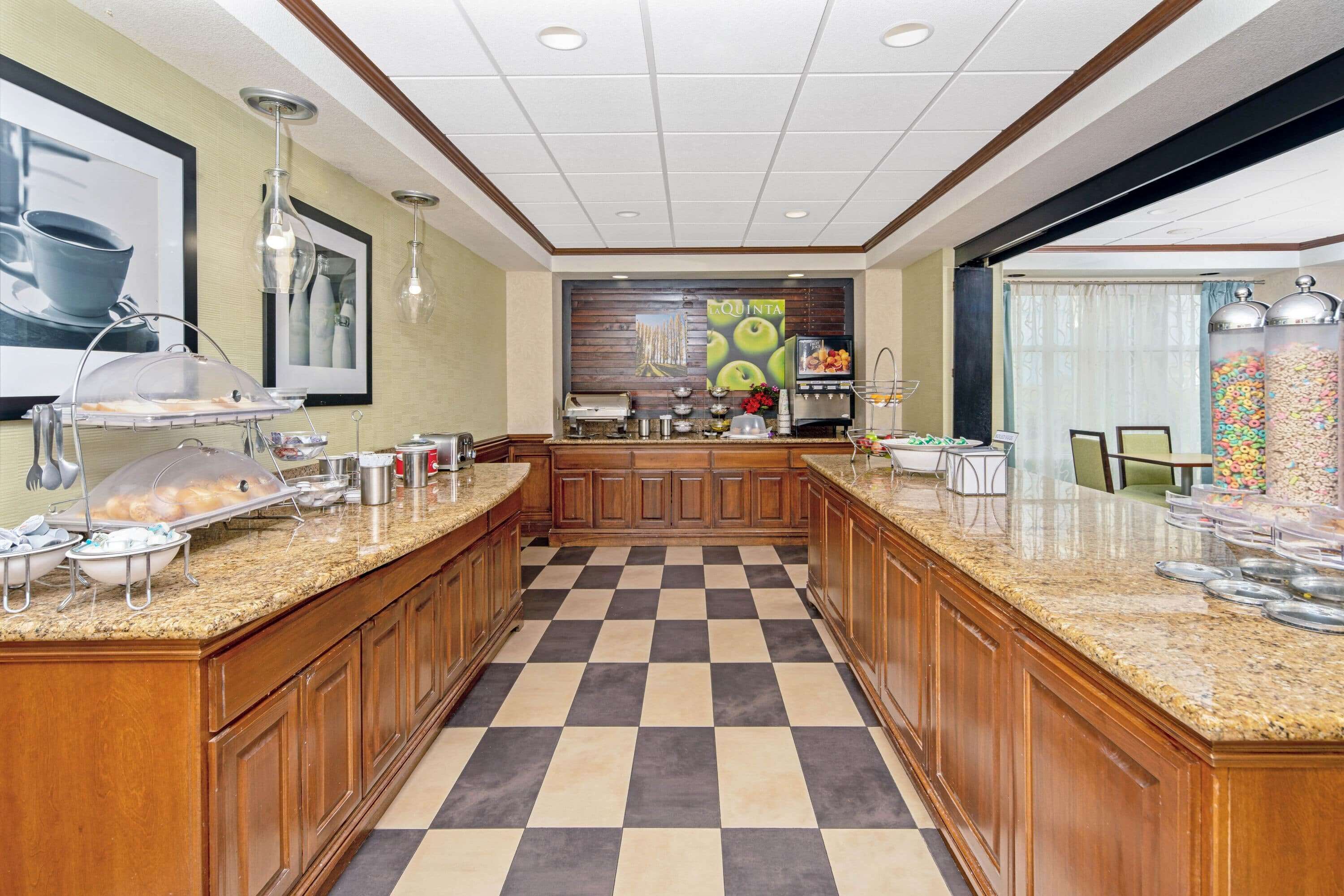 A hotel kitchen with a checkered floor, granite countertops, and various food service equipment.