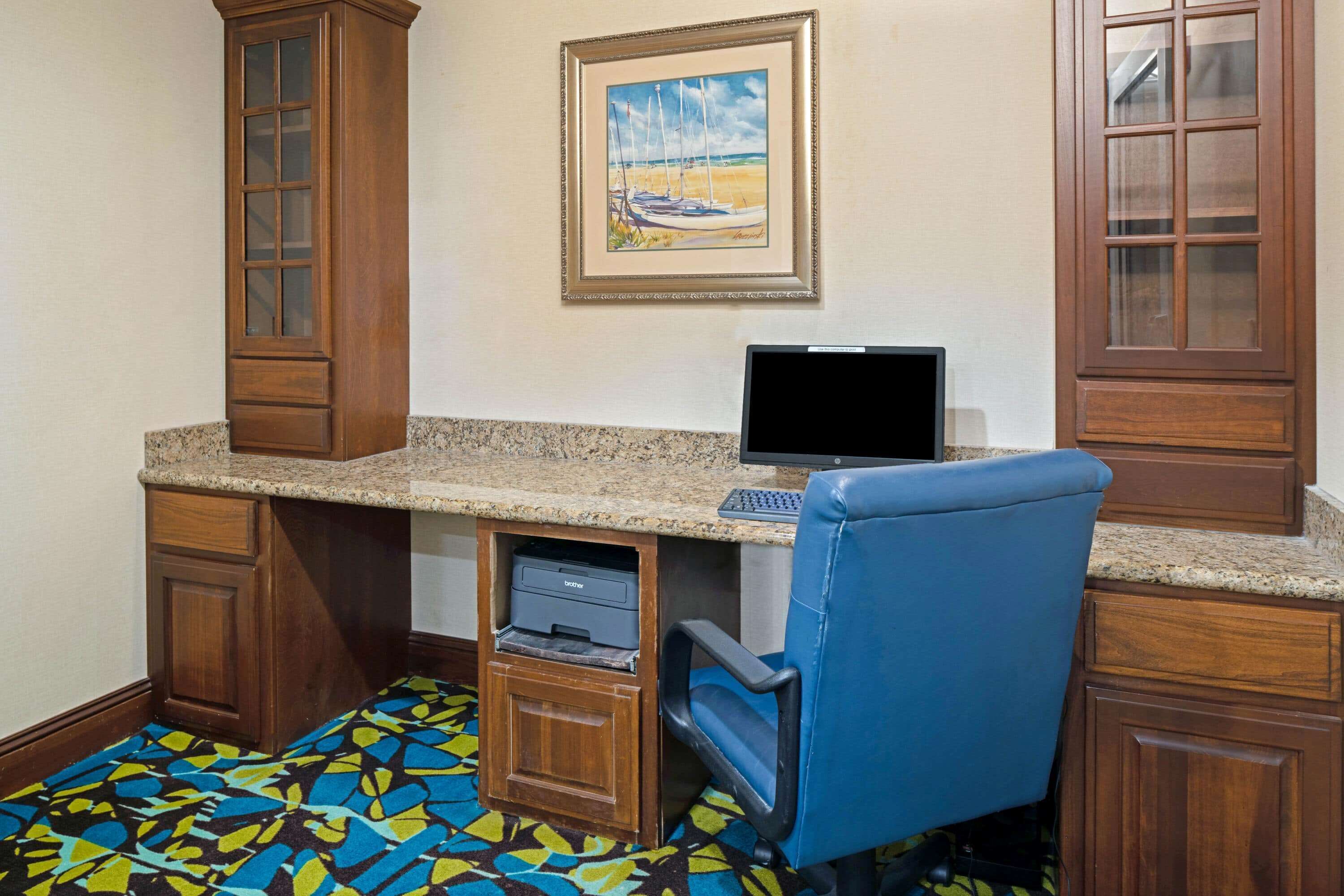 A room with a desk, computer, printer, and a blue chair.