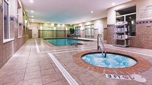 An indoor swimming pool with a hot tub, tiled walls, and a sign indicating a 3 ft depth.
