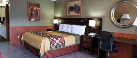 A hotel room with a bed, bedside lamps, a desk with a chair, a mirror, and two framed pictures on the wall.