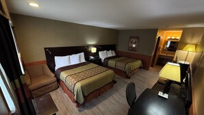 Una habitación de hotel con dos camas, un escritorio, una silla, una lámpara y una mesita.