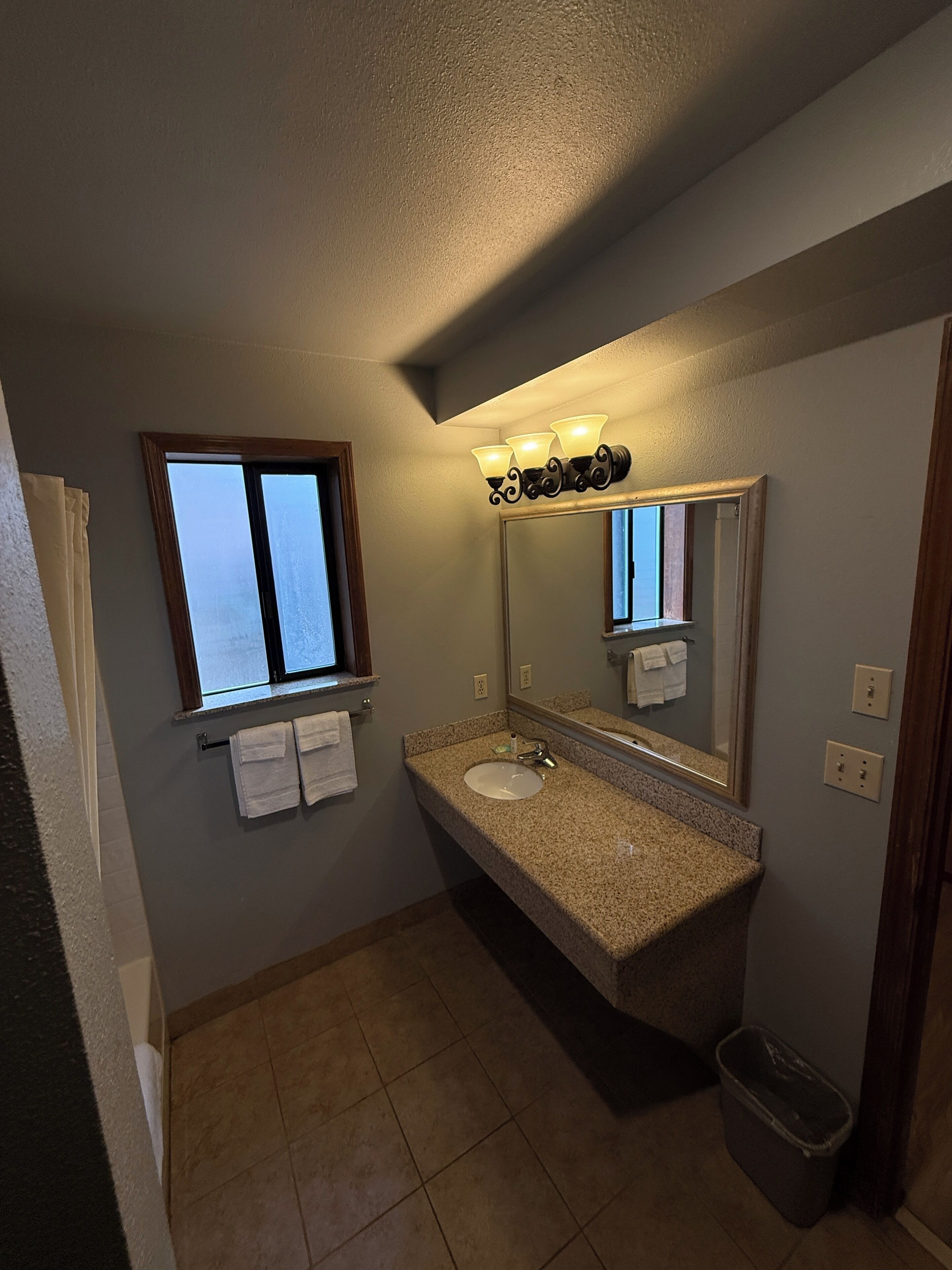 A bathroom with a sink, mirror, and window.