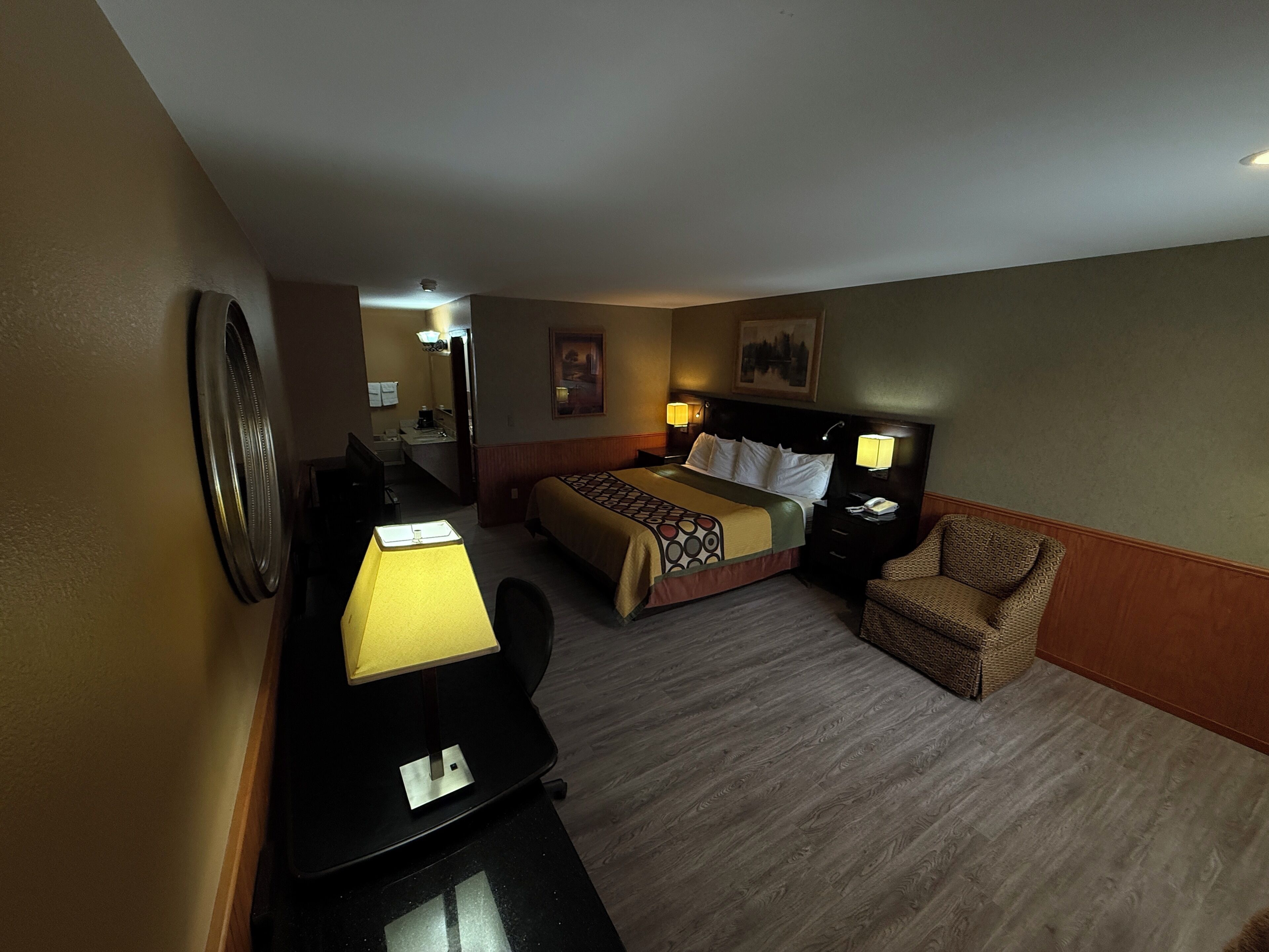Una habitación de hotel con una cama, un escritorio, una silla y una lámpara de escritorio.
